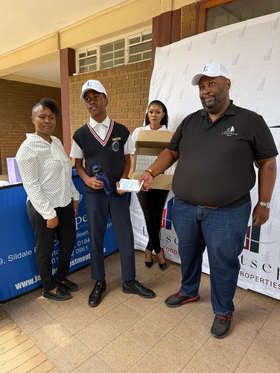 Handing school supplies to a learner at a Letsepe outreach